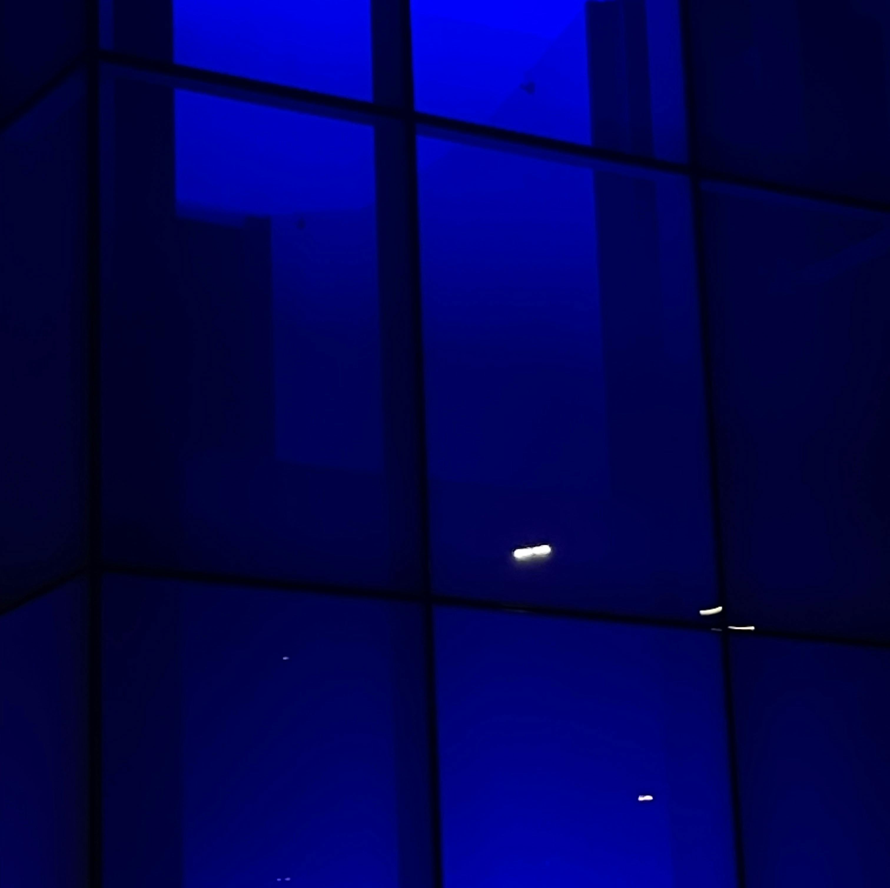 Window with a grid-like pattern illuminated by dark blue light