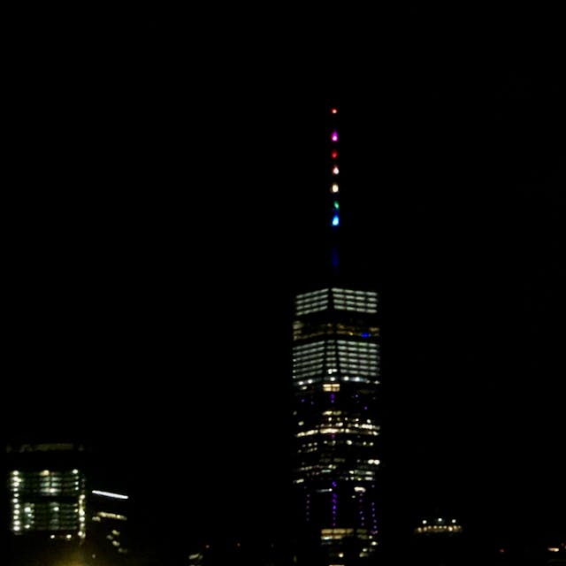The Empire State Building against the night sky with rainbow-colored lights at the top