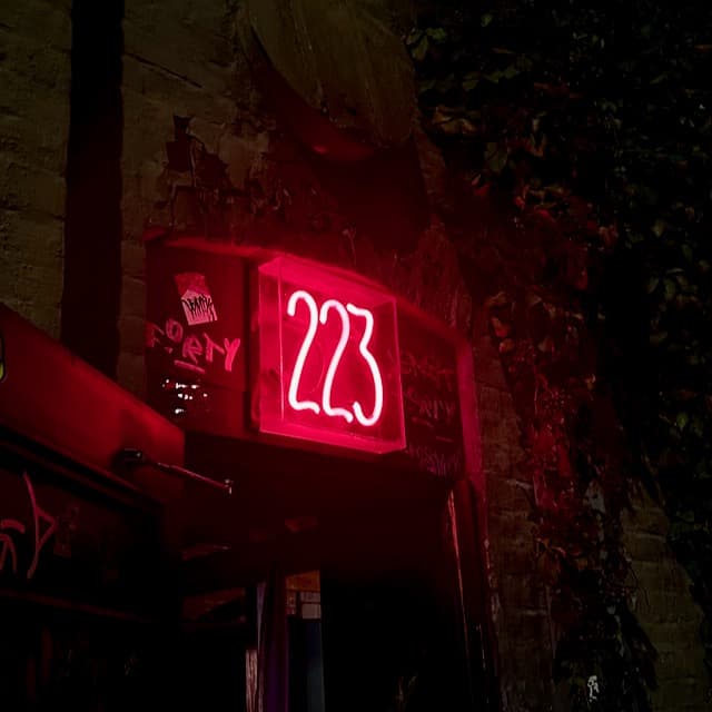 Doorway entrance to Black Sheep in Des Moines. 223 in red neon, surrounded by graffiti