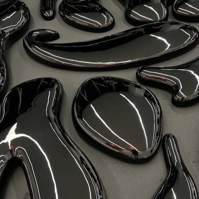 Close-up of shiny, chrome sculptures, with curved forms and reflections.