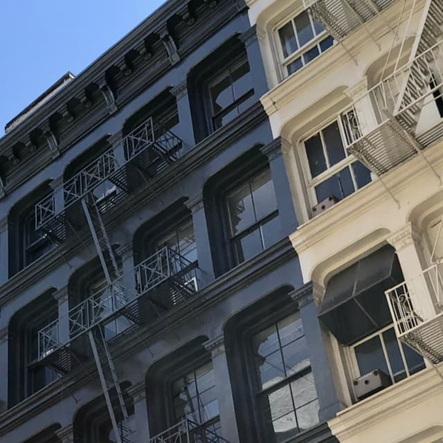 Section of a cast-iron building facade. Two-thirds is covered in all-black paint, the other in all-white.