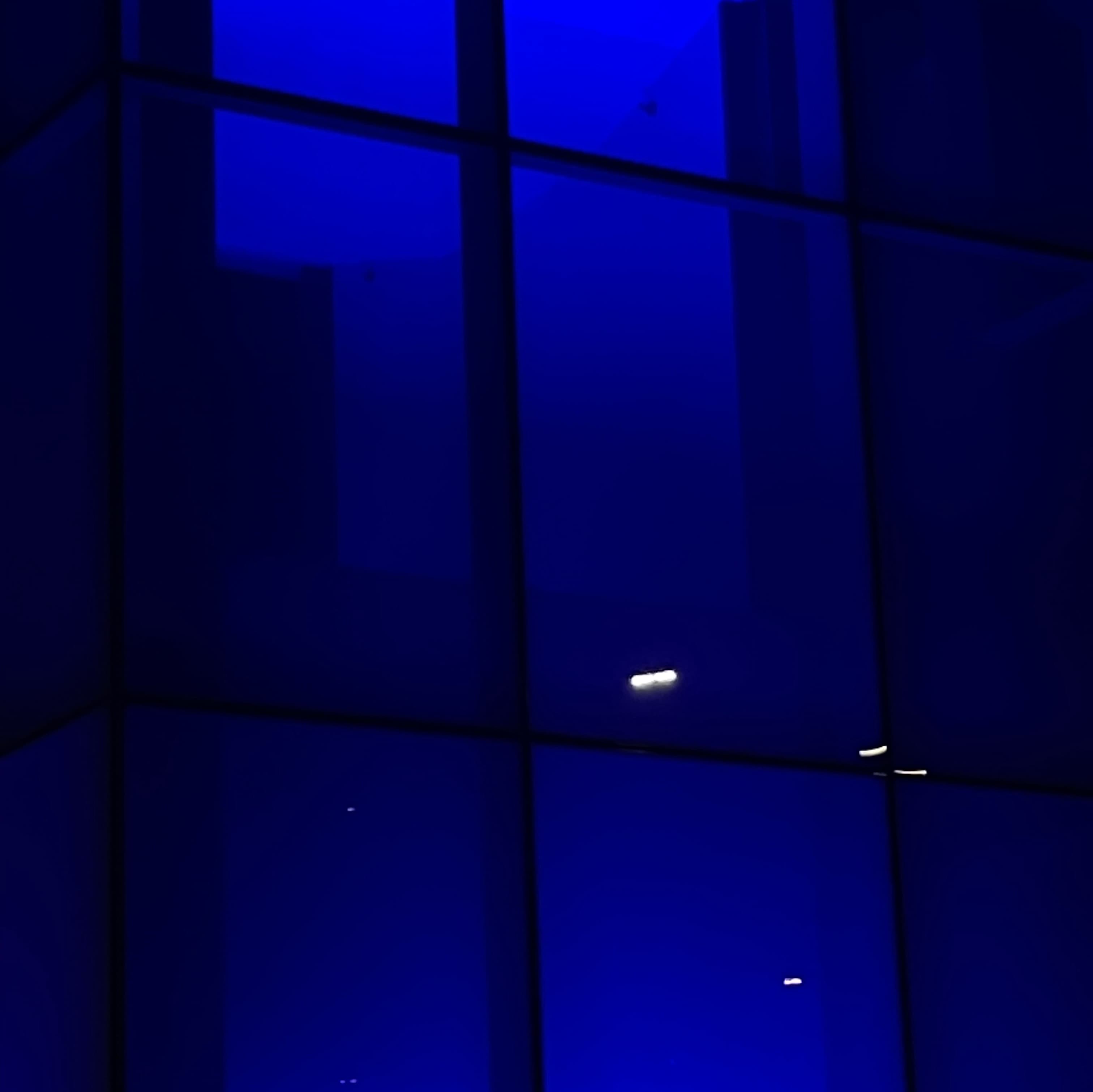 Window with a grid-like pattern illuminated by dark blue light