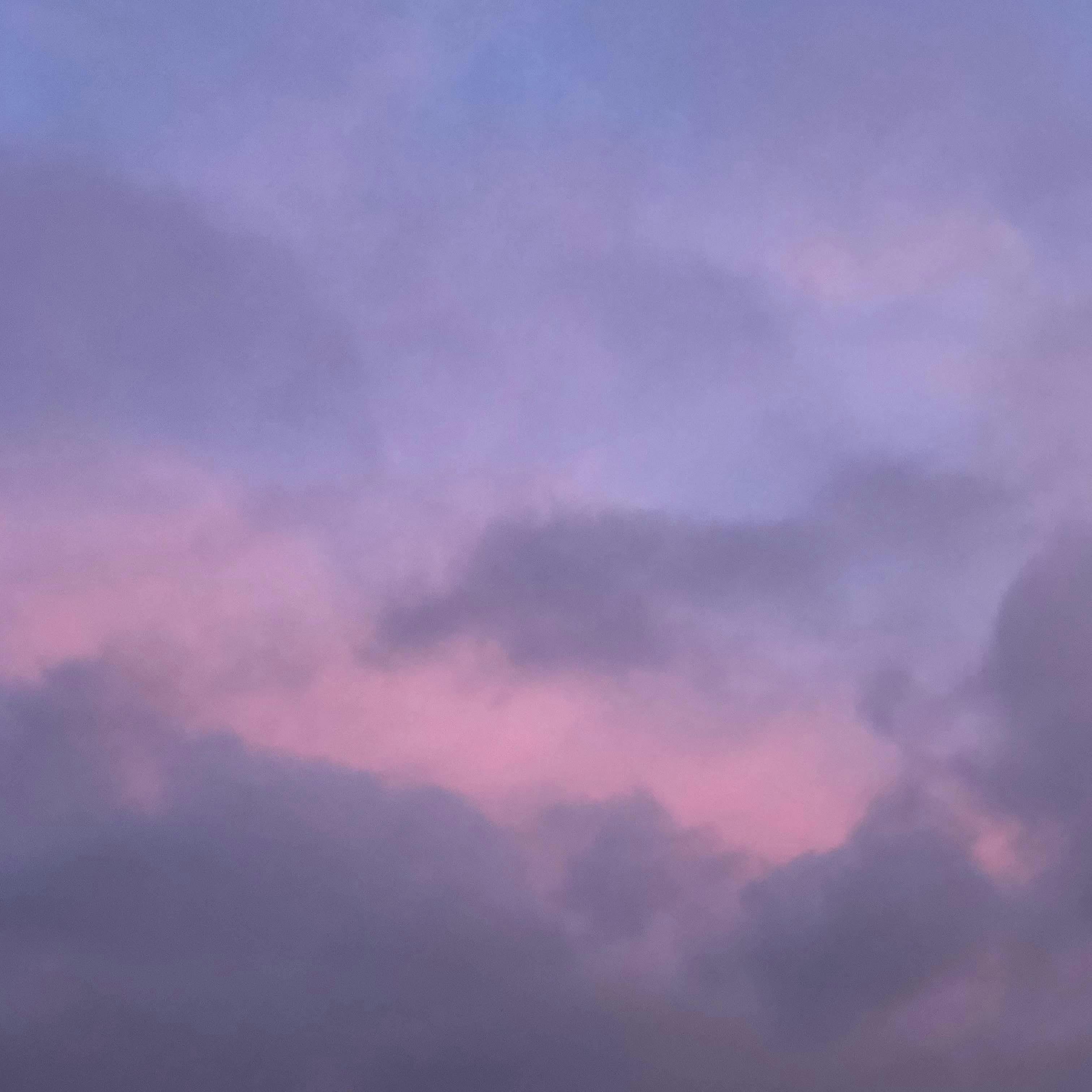A pink and purple sky with puffy clouds at sunset